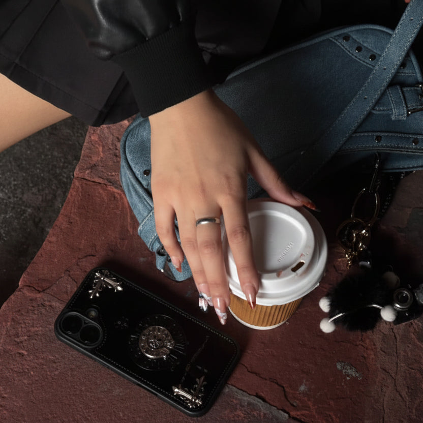 Person sitting with a coffee cup, phone, and handbag on a stone surface.