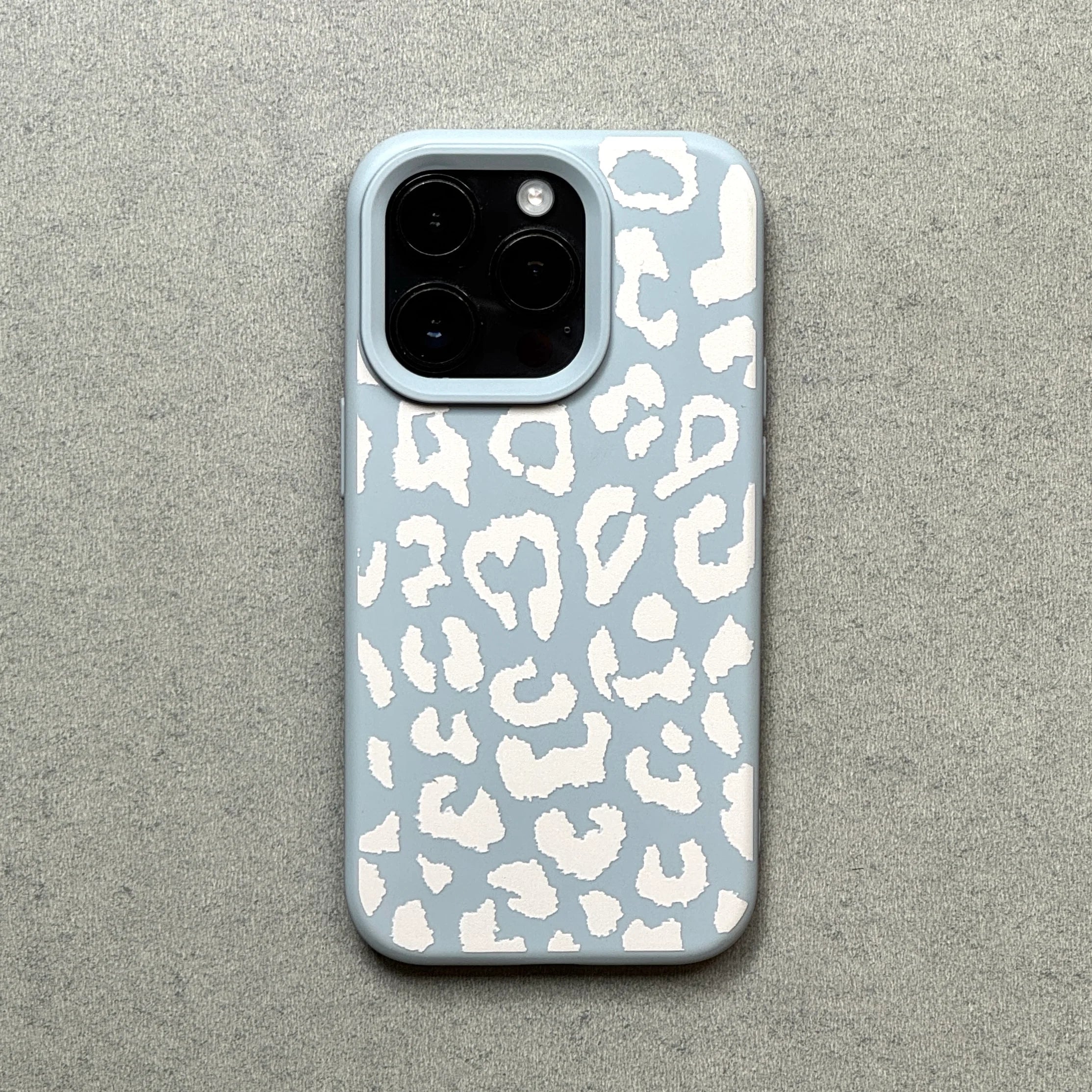 Phone case with white leopard print on a light blue background